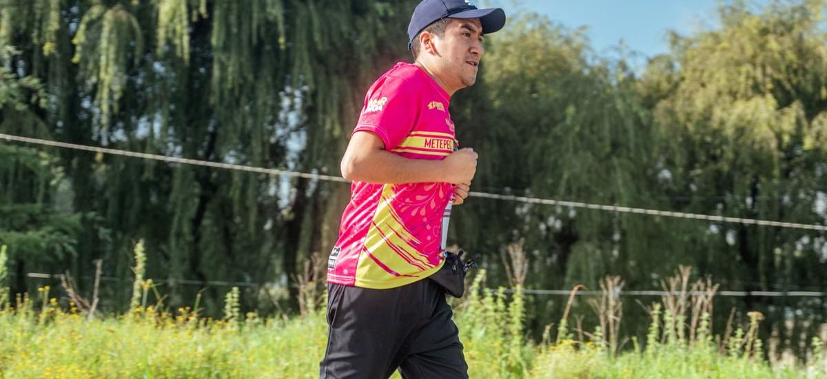 A man in a colorful shirt jogging in a rural area, focusing on endurance and fitness.